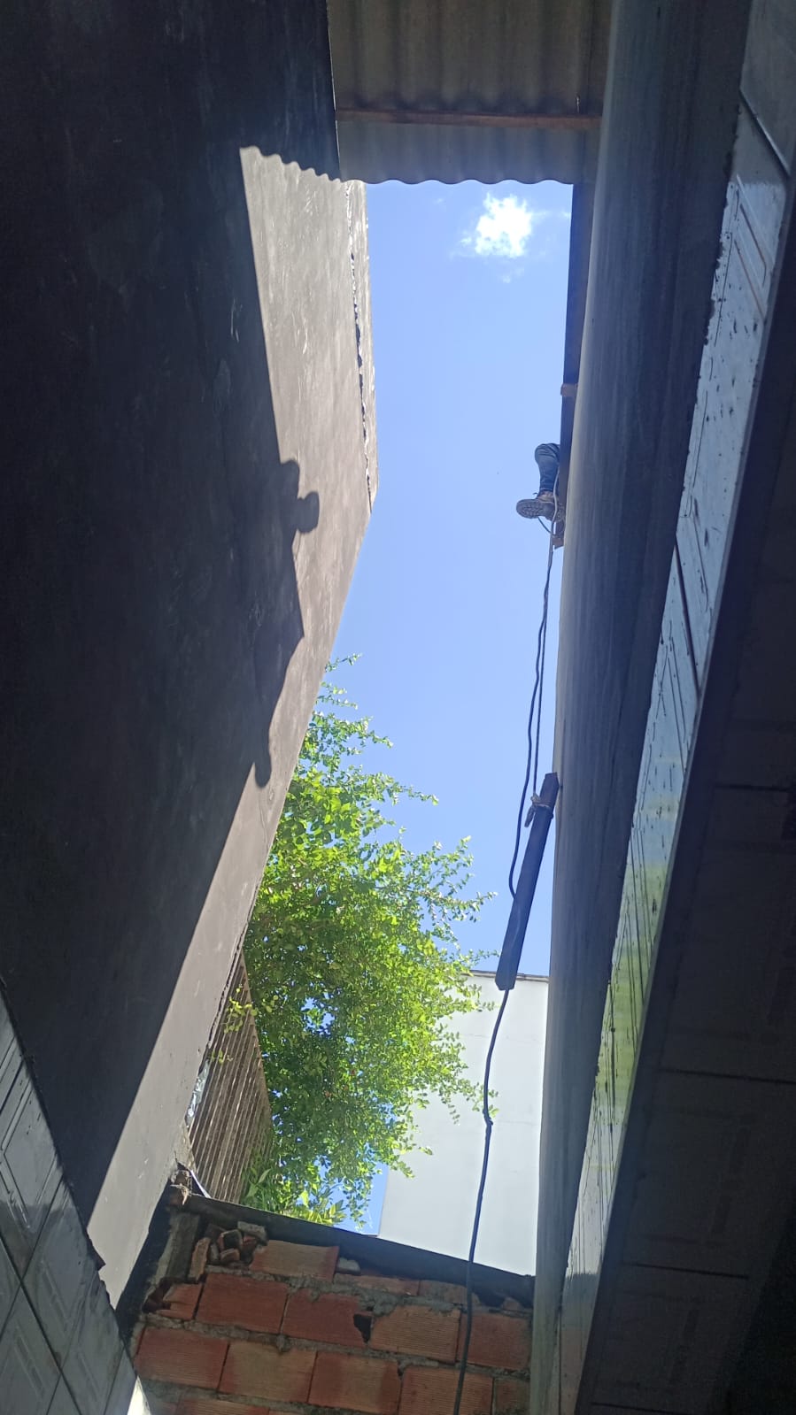 Profissional em cima do telhado durante serviço de limpeza e pintura de calhas