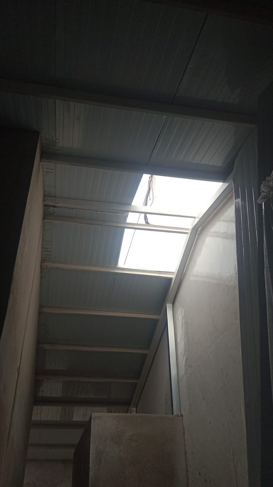 Vista do interior de telhado com estrutura metálica e calha, área típica de trabalho